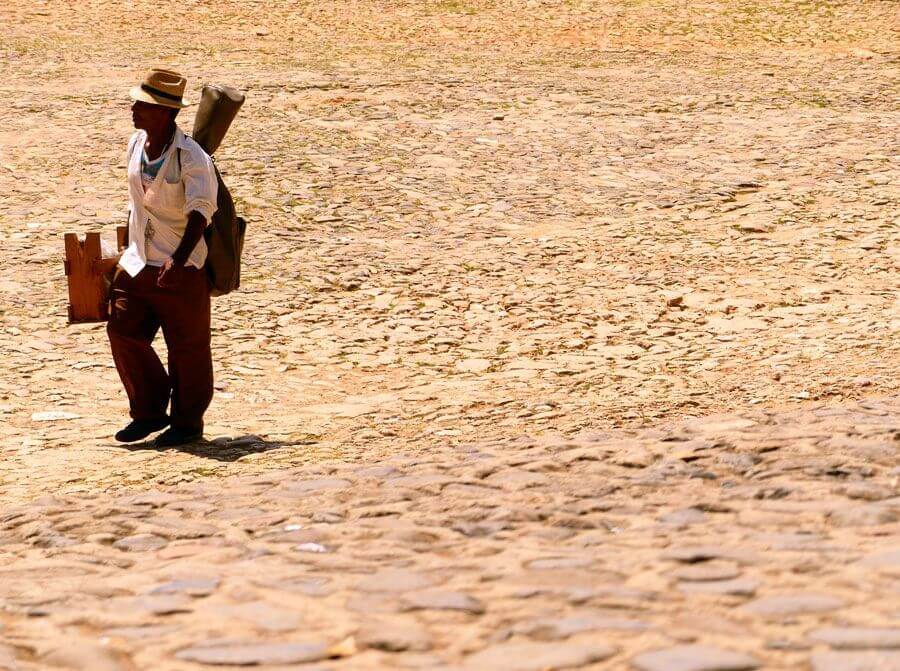 un hombre, músico, caminando por la calle con si bajo