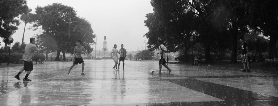 niños jugando al fútbol bajo la lluvia